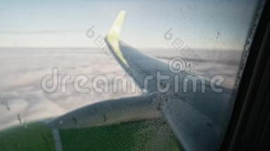 透过窗户看到飞机机翼和云层上有小水滴和一些灰尘